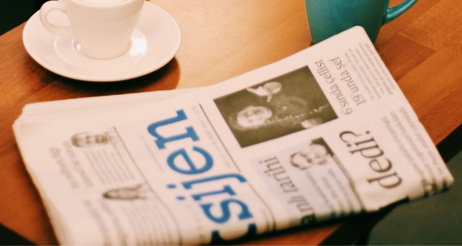 Journal et deux tasses déposés sur une table de salon.